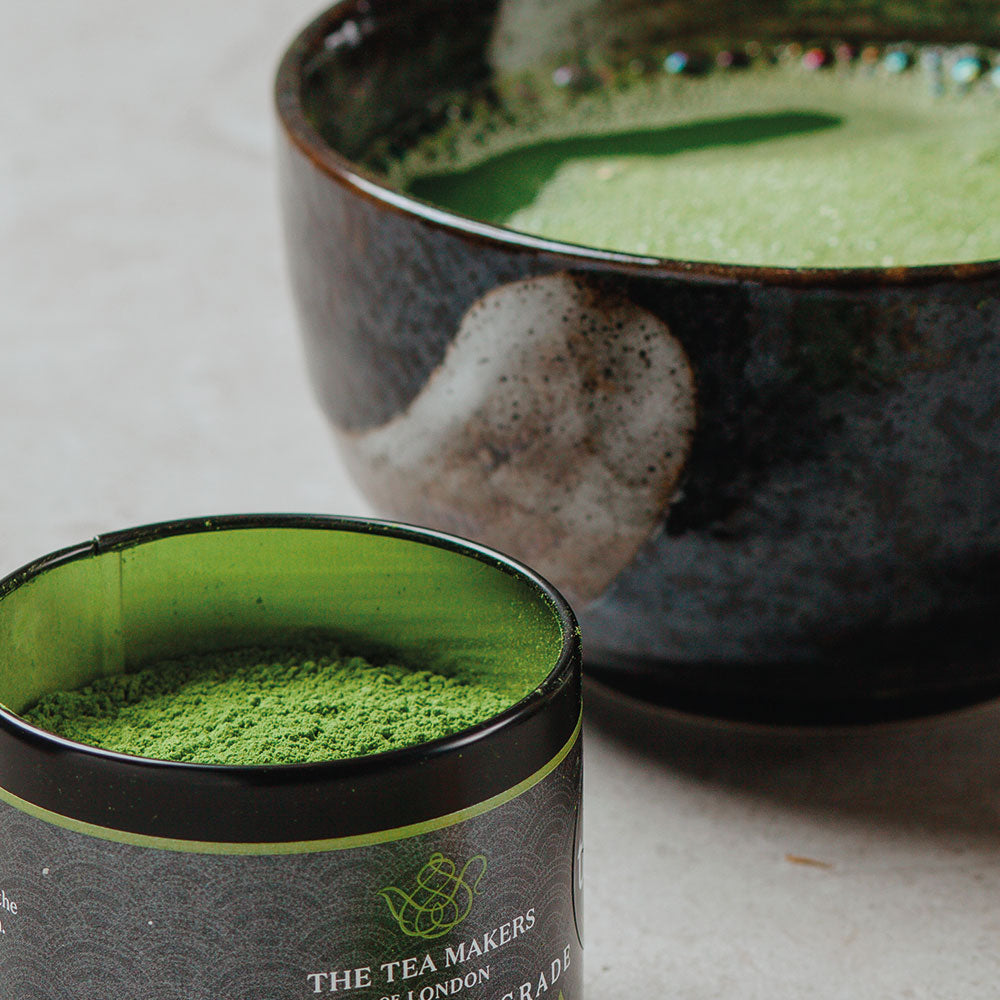 Close-up of 40g Ceremonial Matcha caddy with a full matcha bowl in the background. 